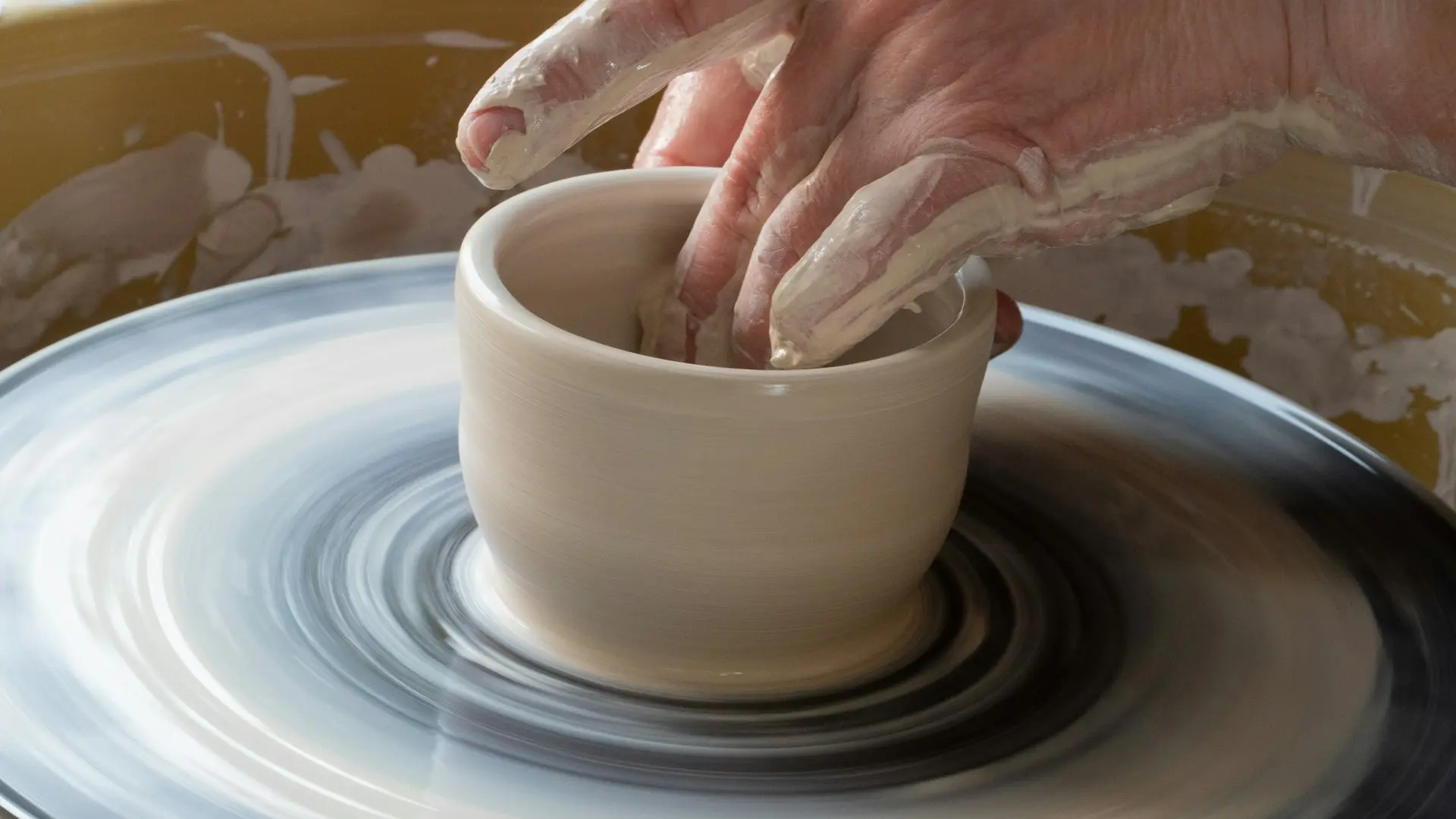 person making clay pot on white round plate